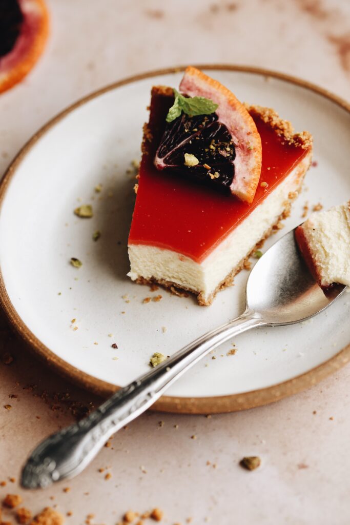 A slice of blood orange cheesecake tart with a spoonful taken out to show the creamy texture inside